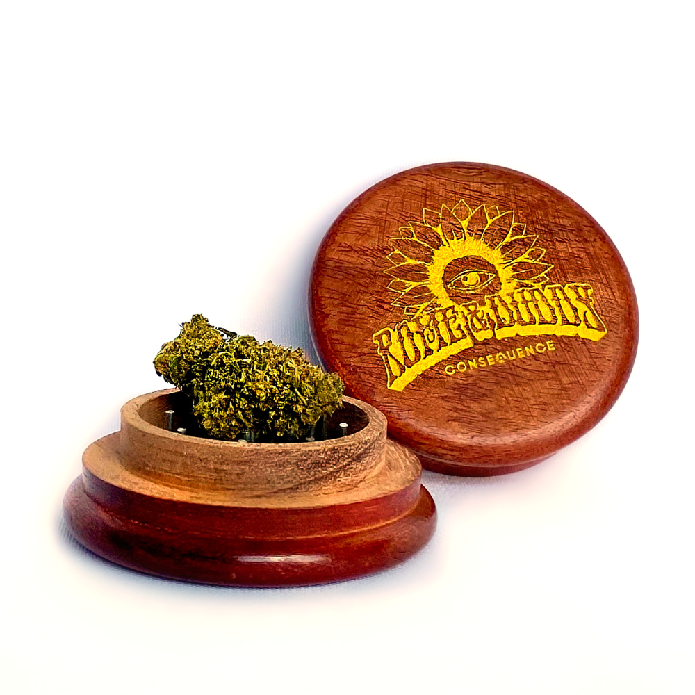 A wooden grinder with two parts, the top part featuring a logo that reads 'Rome & Duddy' with a sun graphic, and the bottom part containing hemp flower.